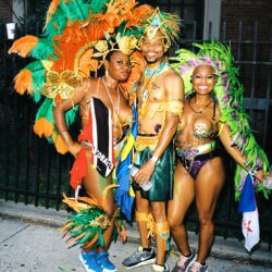 Three people in colorful Caribbean carnival costumes