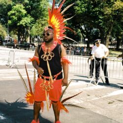 Person in bright orange carnival costume with feathers