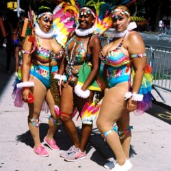 Three women in colorful carnival feather costumes