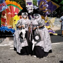 Two masked performers in ornate black-and-white costumes