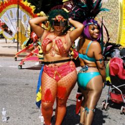 Two women in vibrant carnival feathered costumes