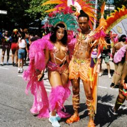 Two dancers in vibrant feathered carnival costumes