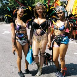 Three women in colorful carnival feathered costumes