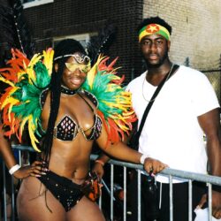 Two people at carnival, woman in feathers