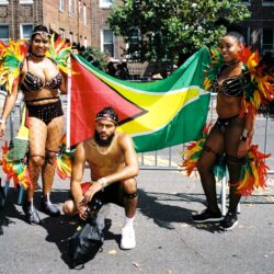 Carnival dancers posing with Guyana flag
