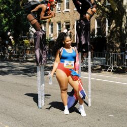Parade stilt performers and woman with flag