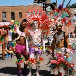 Three carnival dancers in colorful feathered costumes
