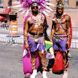 Two men in vibrant feathered carnival costumes