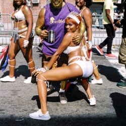 Gold-painted man with street carnival dancers