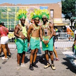 Men in green feathered carnival costumes at parade