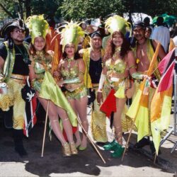 Carnival performers in green costumes holding flags