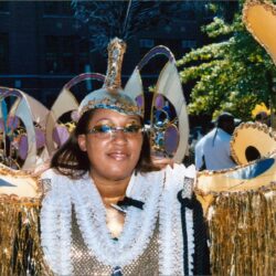Smiling person wearing gold carnival costume and headpiece