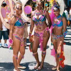 Three women in vibrant carnival parade costumes