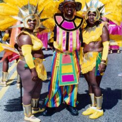 Three carnival performers in yellow feathered costumes