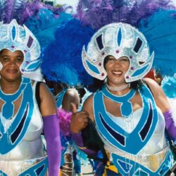 Smiling women in blue feathered carnival costumes