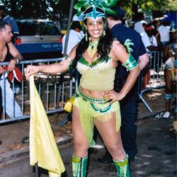 Smiling woman in green carnival costume holding flag