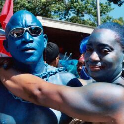 Two people painted blue embracing at festival
