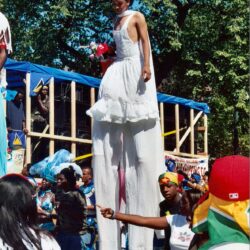Stilt walker in white dress at street parade