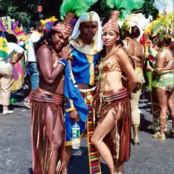 Three costumed carnival performers with feathered headdresses