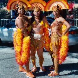 Three women in orange and yellow carnival costumes