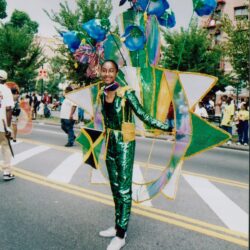 Parade participant in green costume with floral wings