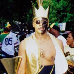 Person wearing gold crown, costume, and sunglasses