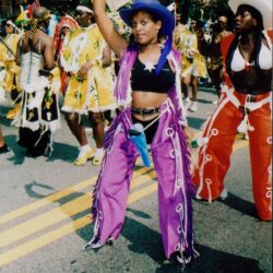 Colorful carnival dancers marching down city street