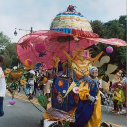 Colorful parade performer wearing oversized umbrella costume