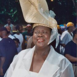 Smiling woman in large hat and white outfit