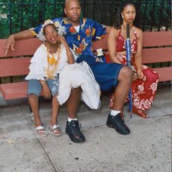 Family sitting on a park bench together.