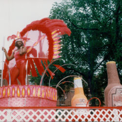 Parade float with performers in red feathered costumes