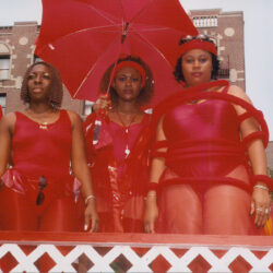 Three women in red outfits with red umbrella