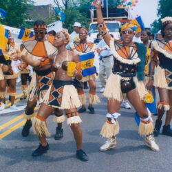 Street carnival dancers in straw costumes with flags