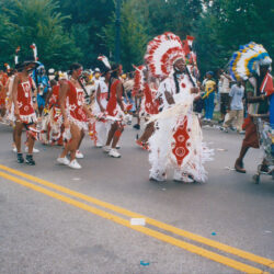 Parade participants wearing colorful feathered headdresses
