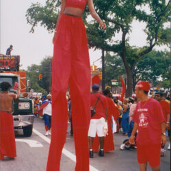 Performer on red stilts at street parade