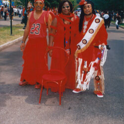 Three people in red ceremonial outfits outdoors
