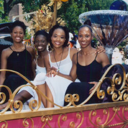 Four women smiling on ornate parade float
