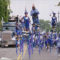 Parade performers on stilts in colorful costumes.