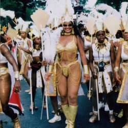 Carnival parade with dancers in gold costumes.