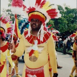 Man in colorful costume at outdoor parade.