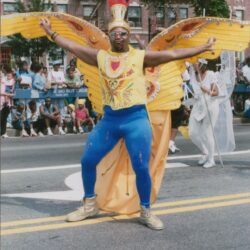 Carnival performer with colorful wings on street.