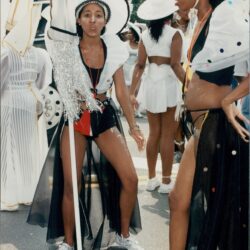Women in elaborate costumes at outdoor event.
