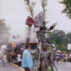 Parade with large insect-like costume and spectators.
