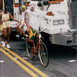 Man cycling beside a large truck.