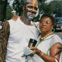 Man with face paint and woman outdoors.