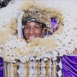 Person in elaborate, colorful festival costume smiling.