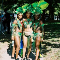 Three people in green carnival costumes outdoors.
