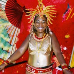 Carnival performer in vibrant red and gold costume.