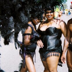 Two smiling women in black feathered carnival costumes