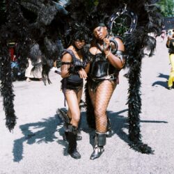 Two performers in black feathered carnival costumes